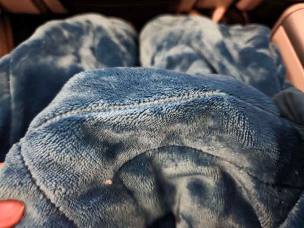 WestJet Premium Economy welcome setup with blanket, pillow and drink