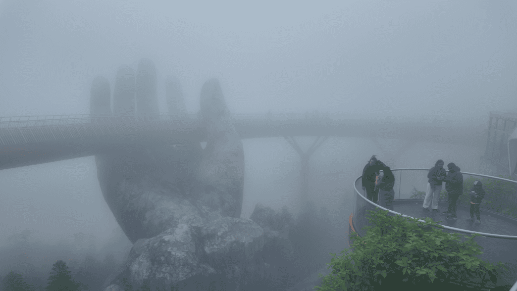 Golden Bridge held by giant stone hands in thick fog, Ba Na Hills, Vietnam