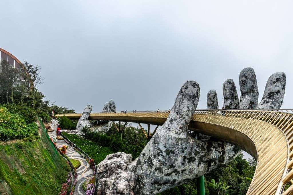Explore the iconic Golden Bridge in Da Nang, Vietnam, held by giant stone hands amidst lush greenery.