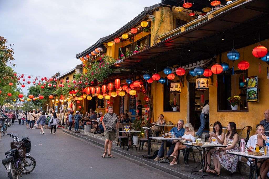 Festive outdoor café in Hoi An with colorful lanterns and street life ambience.