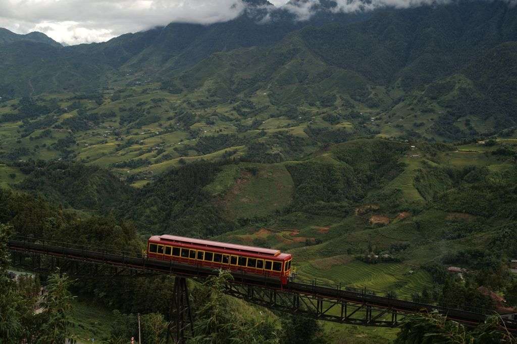 Picturesque view of a train crossing a bridge in lush Lào Cai, Vietnam's mountains.