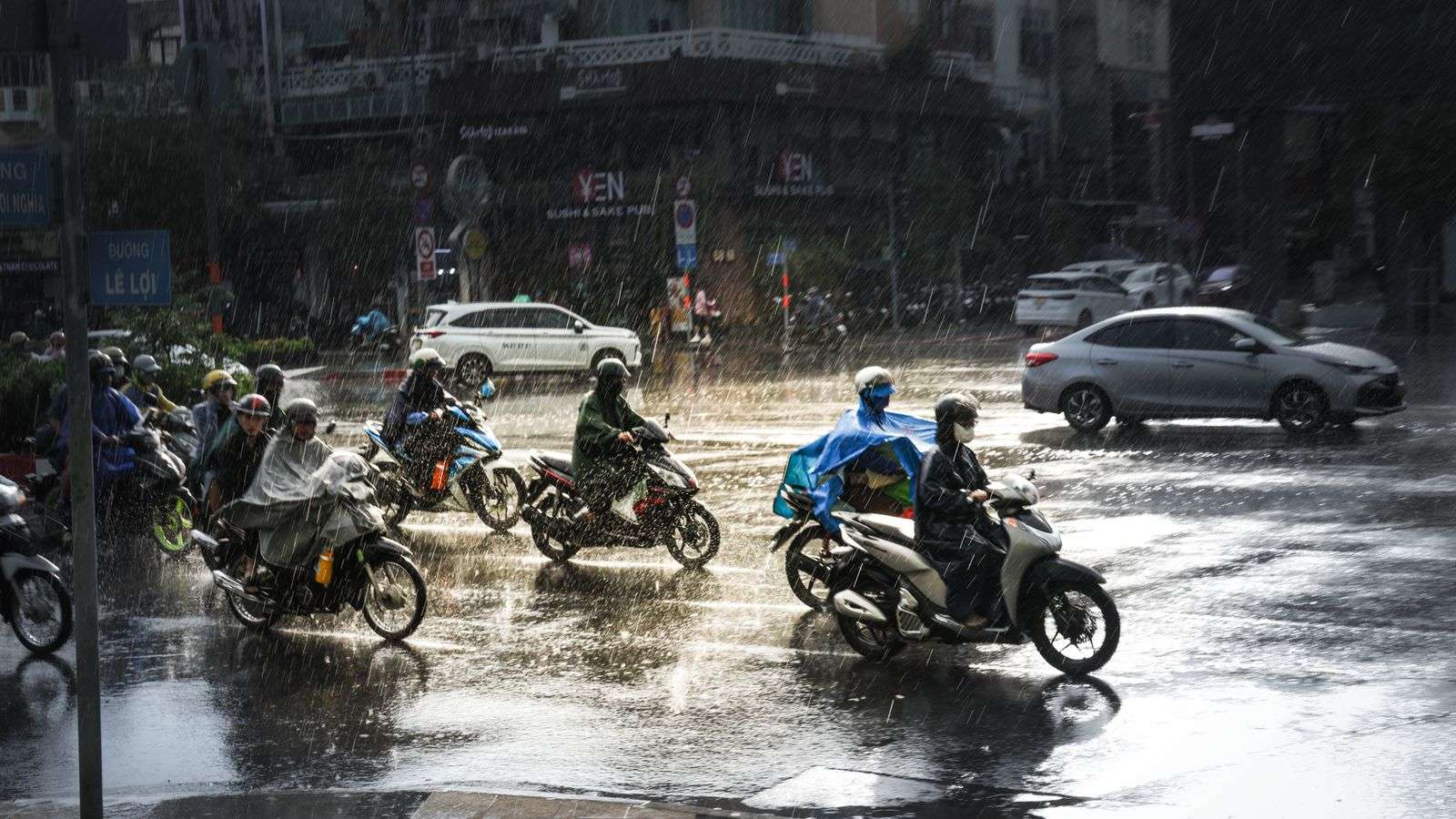 Motorcyclists riding through heavy rain during Vietnam typhoon season in Ho Chi Minh City